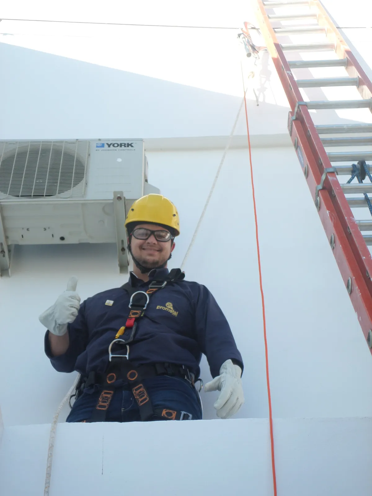 Trabalhador em altura sorrindo, usando capacete e equipamento de proteção Prometal EPIs