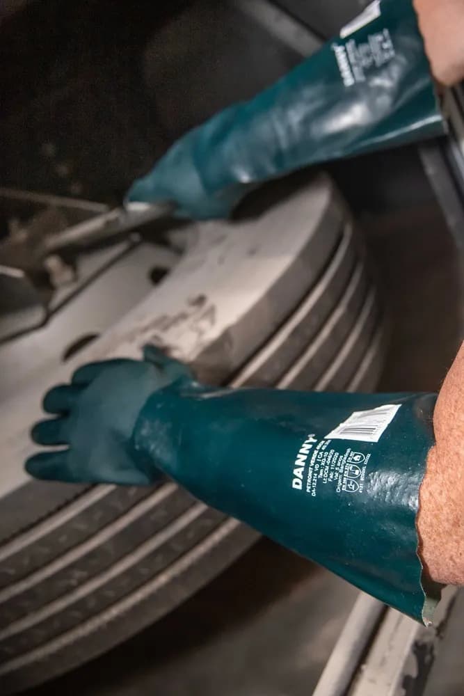 Luvas verdes Danny de proteção química em uso na manutenção de um pneu